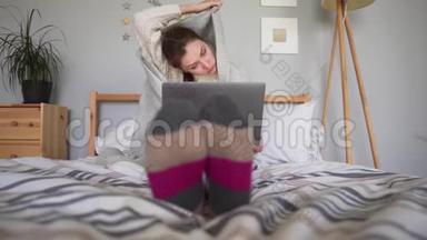 可爱的女孩用毯子<strong>盖</strong>上<strong>被子</strong>，想着生意，看着笔记本屏幕。 穿睡衣的女人，